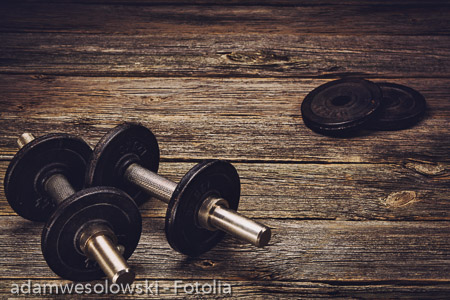 Old iron dumbbells on an old wooden table. Image taken from above, low angle .