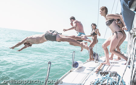 Friends jumping in the water from the boat