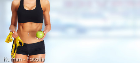 Woman abdomen with measuring tape and apple.