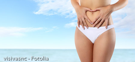 woman hands heart shape on belly, isolated on summer sea and sky background