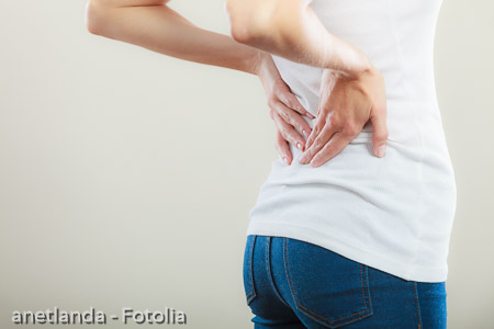 Backache. Young woman suffering from back pain