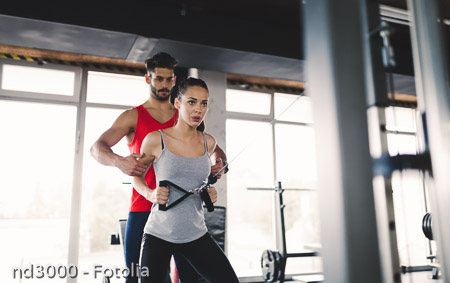 Personal trainer assisting woman lose weight