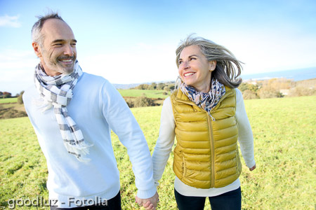 Cheerful senior couple running in countryside