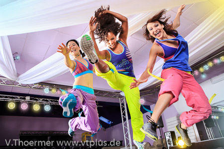 young women in sport dress jumping at an aerobic and zumba exerc