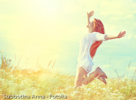 Beauty model girl in white dress jumping on summer field
