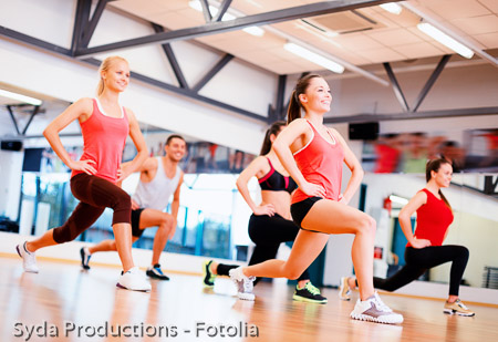 group of smiling people exercising in the gym