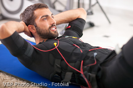 young fit man exercise on  electro muscular stimulation machine
