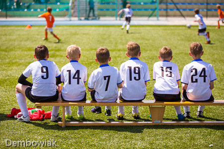 Football soccer match for children. Kids waiting on a bench.
