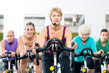 Senior people in gym spinning on fitness bike 