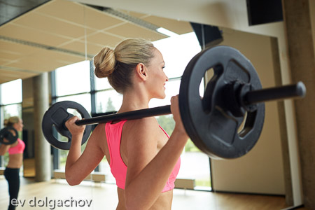 sporty woman exercising with barbell in gym