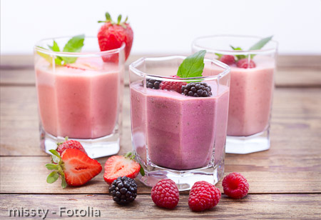 Drink smoothies four summer strawberry, blackberry, kiwi, raspberry on wooden table.