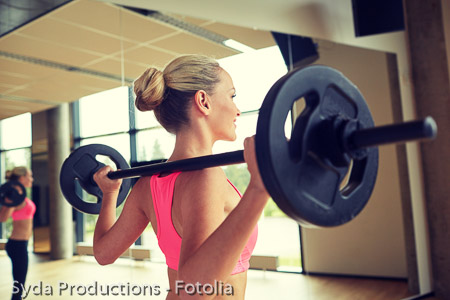 sporty woman exercising with barbell in gym