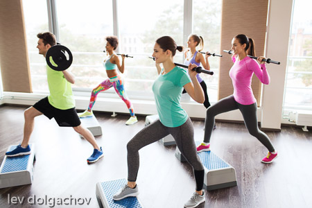group of people exercising with barbell in gym
