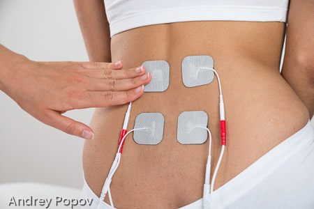 Therapist Placing Electrodes On Woman's Back