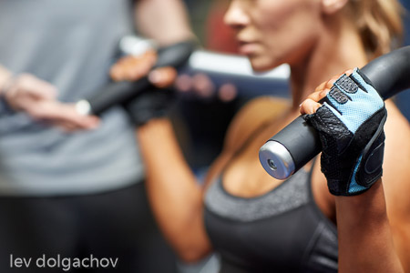 man and woman flexing muscles on gym machine
