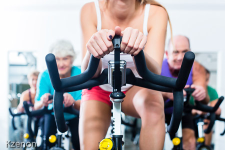 Senior people in gym spinning on fitness bike