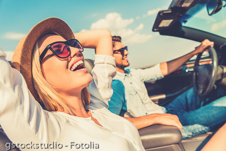 Freedom of the open road. Side view of joyful young woman relaxing on the front seat while her boyfriend sitting near and driving their convertible 