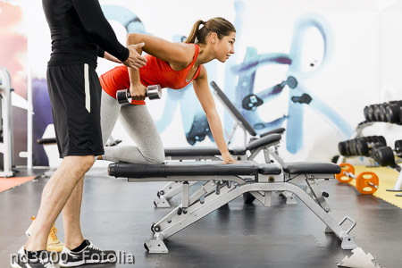 Young male trainer giving instructions to a woman in a gym