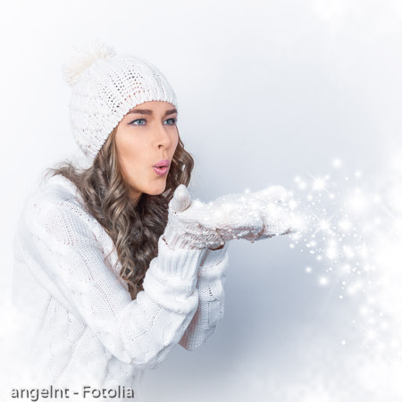 beautiful girl blows off snowflakes from hands